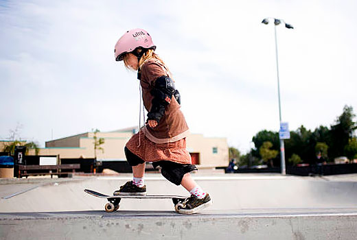 Девочка едет на скейте в Triple8 Little Tricky Pink Rubber